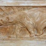 AN EARLY 20TH CENTURY RELIEF MOULDED PLASTER PLAQUE OF A POLAR BEAR