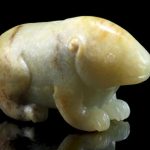 A mottled green and russet jade carving of a bear